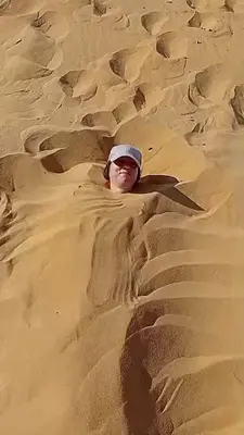 a man laying in the sand in the desert at Esmerada in Aswan