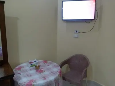 a table and a chair and a television on a wall at Kazpilkna Beach Neighborhoods in Hurghada