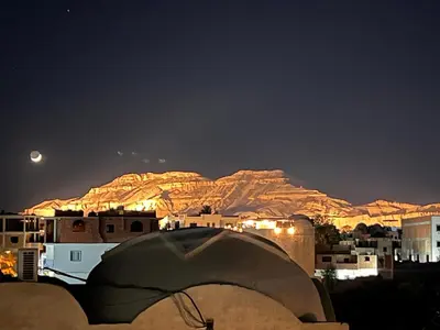 a view of a city at night with the moon at Muhammad Ali House in Luxor