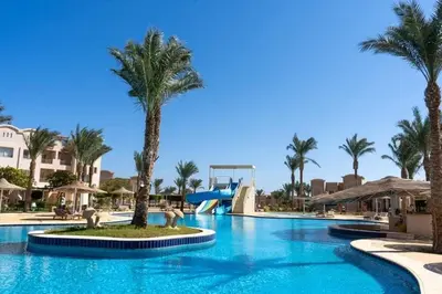 a pool at a resort with palm trees and a slide at Sunset pearl, Sahl Hashish in Hurghada