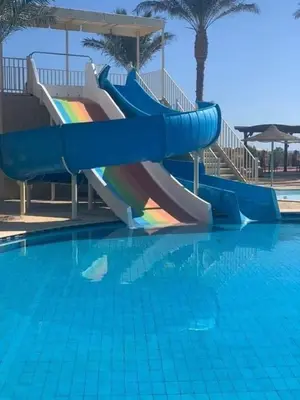 a slide in a swimming pool with a rainbow at Sunset pearl, Sahl Hashish in Hurghada