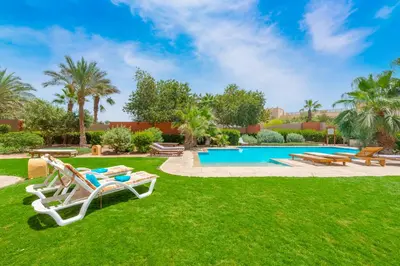 a yard with lawn chairs and a swimming pool at Charming Apartment with Pool in prime location in Hurghada