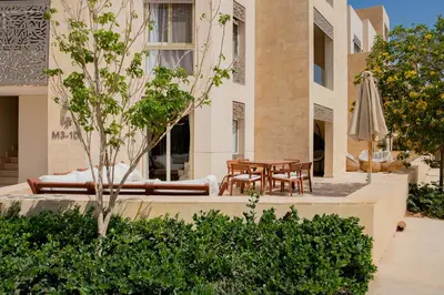 a patio with a table and chairs and an umbrella at Apartment with large terrace & nice pool area in Hurghada