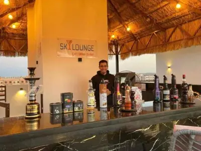 a man standing behind a bar with bottles of alcohol at Studio Sleeps 2 with Balcony Pool & Parking in Hurghada