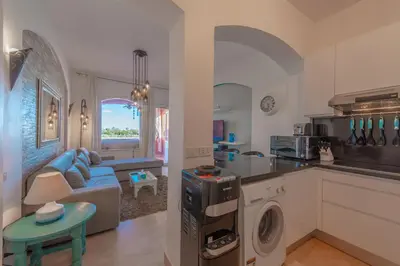 a kitchen and living room with a blue couch and a table at Special style apartment with pool at lagoon in Hurghada