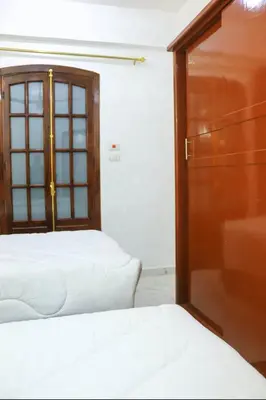 a bedroom with two beds and a wooden door at Shahd House in Luxor