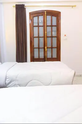 a bedroom with two white beds and a window at Shahd House in Luxor