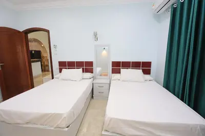 two beds in a room with green curtains and a mirror at Ramsses Palace in Luxor