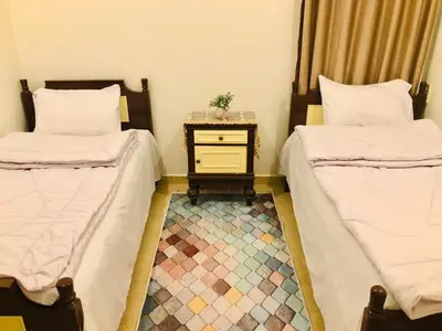 two beds in a room with a table between them at joy house in Luxor