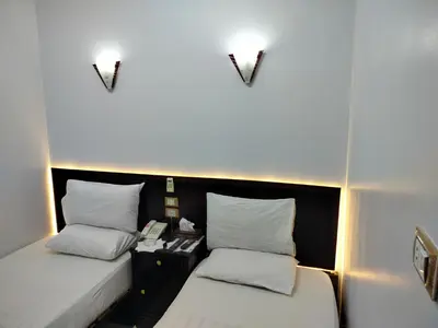 a small room with two beds and a telephone at Abo Elwafa Hotel in Suwhaj
