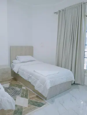 a white bedroom with a bed and a window at جوليانا بيتش ريزورت in Hurghada