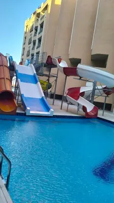 a swimming pool with a slide and some chairs at جوليانا بيتش ريزورت in Hurghada