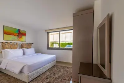 a white bedroom with a bed and a television at El Gouna Luxury flat on the pool in El Gouna