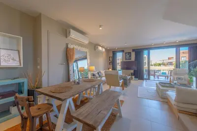 a living room with a wooden table and chairs at Ultimate Beachstyle Getaway Gouna 2BR Twinhouse. BBQ, Lagoon & Pool Access in Hurghada
