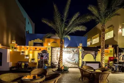 a patio with tables and palm trees in front of a building at Private 3 bdrm apartment at ElKarma Aqua Beach Reaort in Hurghada