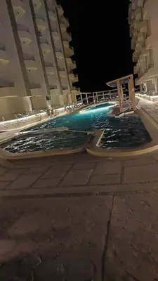 a swimming pool in front of a building at night at La Quinta Resort Hurghada in Hurghada