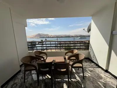 a balcony with a table and chairs and a view of the water at Relaxation, fresh air, and a direct view of the Nile in Naj‘ al ‘Amrāb