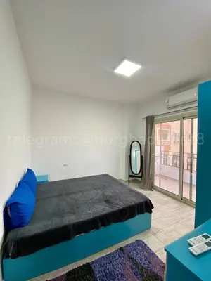 a bedroom with a blue bed and a large window at Makramia Compound in Hurghada