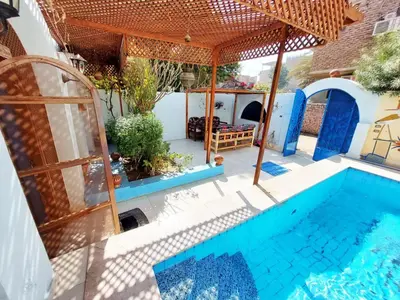 a house with a swimming pool and an umbrella at Villa Cleopatra Luxor west bank in Luxor