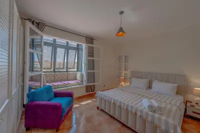 a bedroom with a bed and a chair and a window at SeaView Penthouse with Roof in Marina El Gouna Egypt (Center) in Hurghada
