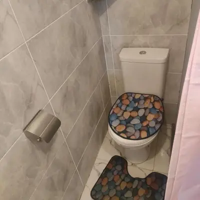 a bathroom with a toilet with a seat covered in rocks at Hurghada Palma Resort Studio in Hurghada