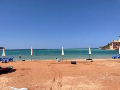 a beach with umbrellas and people in the water at Villa 2 apartment 4 village veiw infront of Palma de Meritee in Hurghada