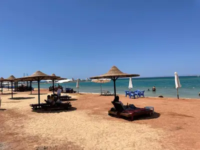a beach with people sitting on chairs and umbrellas at Villa 2 apartment 2 village veiw infront of Palma de Meritee in Hurghada