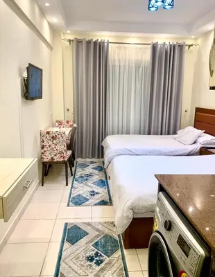 a hotel room with two beds and a chair at Studio Pool view with balcony Florenza Hurghada in Hurghada