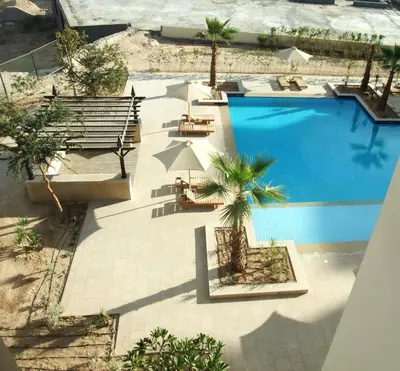 an overhead view of a pool with a bench and palm trees at AlDau heights Maher in Hurghada