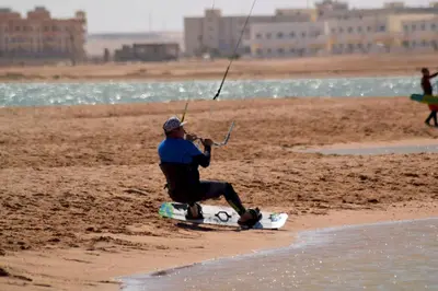 a man sitting on a surfboard on the beach at Pool view studio with terrace in Hurghada