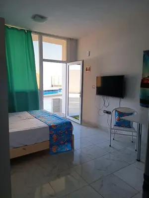 a bedroom with a bed and a tv and a chair at Pool view studio with terrace in Hurghada
