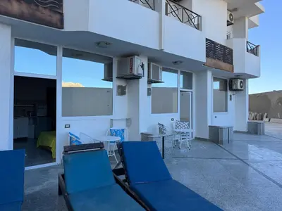 a patio with blue chairs and a table at Pool view studio with terrace in Hurghada