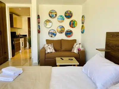 a bedroom with a bed and a couch and plates on the wall at A Bright Studio @GCribs - El Gouna W/ Shared pool! in El Gouna
