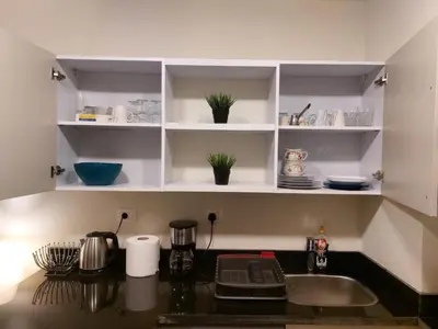 a kitchen counter with a sink and white shelves at Cozy, Calm, Studio in Veranda Sahl Hasheesh Resort in Hurghada