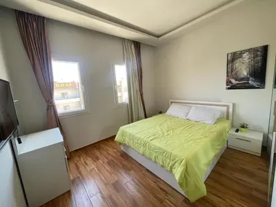 a bedroom with a bed with a green bedspread and two windows at Modern HOME DownTown in Hurghada