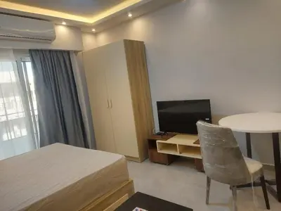 a bedroom with a bed and a table and a television at Makramia New Studio near to the beach in Hurghada