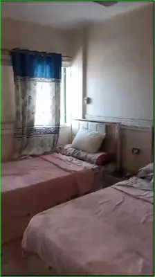a bedroom with two beds and a window with a curtain at 