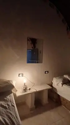 a room with two beds and a table with a lamp at Ezzo Nubian guest house in Aswan