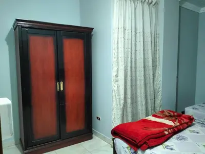 a bedroom with a bed and a wooden cabinet at Eldon apartment in Hurghada