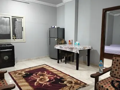 a living room with a table and a refrigerator at Eldon apartment in Hurghada