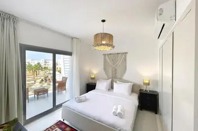 a bedroom with a white bed and a large window at Charming & Beautifully Styled 3BDR Swan Lake Gouna in Hurghada