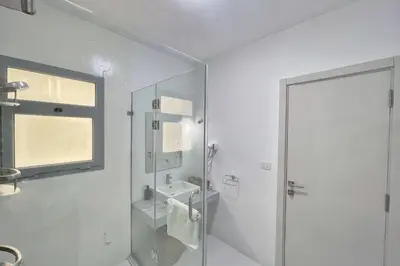 a white bathroom with a shower and a sink at Charming & Beautifully Styled 3BDR Swan Lake Gouna in Hurghada