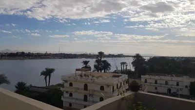 a view of a building and a river with palm trees at Elminaa Residence 6 in Luxor