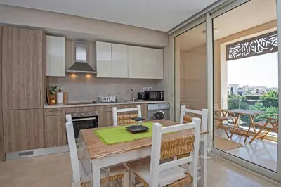 a kitchen with a table and chairs and a kitchen with a balcony at Ollystays Mangroovy 1 BR Beach and Pool Free access in Hurghada