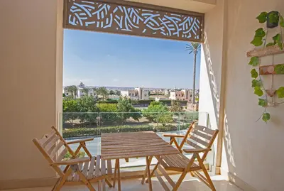a balcony with a table and chairs and a large window at Ollystays Mangroovy 1 BR Beach and Pool Free access in Hurghada