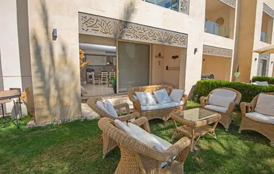 a patio with wicker chairs and tables on the grass at Ollystays Mangroovy 2 BR Beach and Pool Free access in Hurghada
