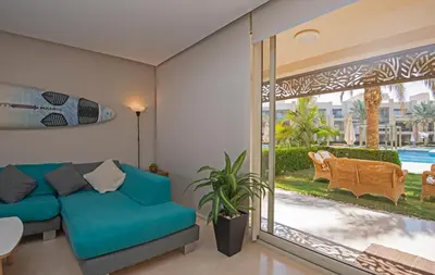 a living room with a blue couch and a large window at Ollystays Mangroovy 2 BR Beach and Pool Free access in Hurghada