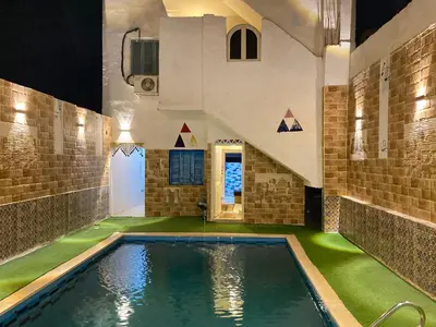 a swimming pool in a house with green flooring at Bakar House in Aswan