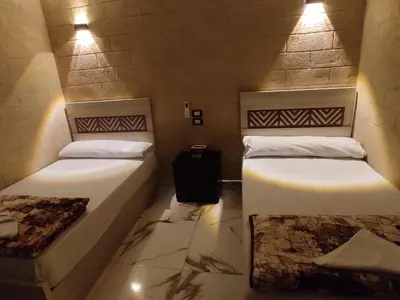 two beds in a small room with lights at Bakar House in Aswan