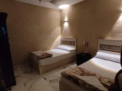 a bedroom with two beds and a stone wall at Bakar House in Aswan